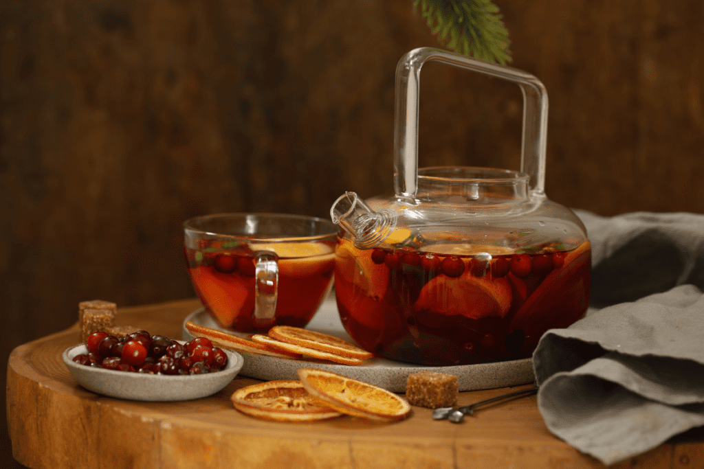 Ceainic și cană din sticlă cu ceai de merișoare în cadru rustic. Ceaiului de merișoare