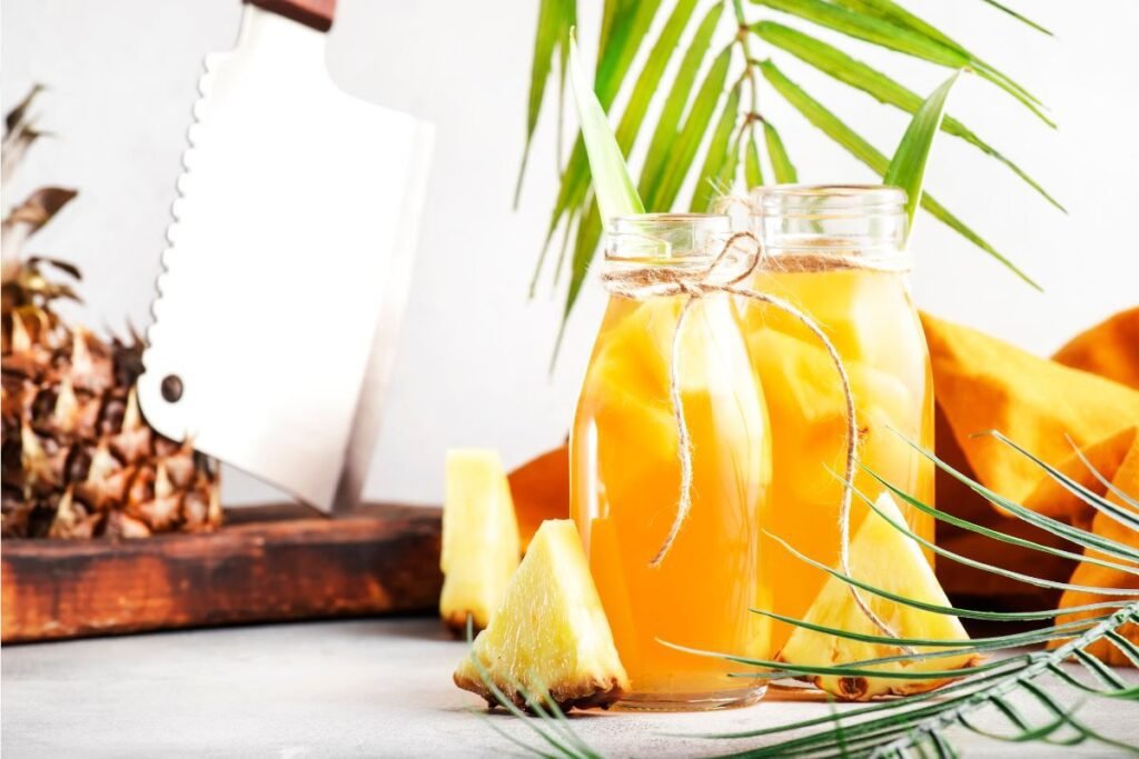 Două carafe înalte, tip sticlă pline cu ceai rece din ananas