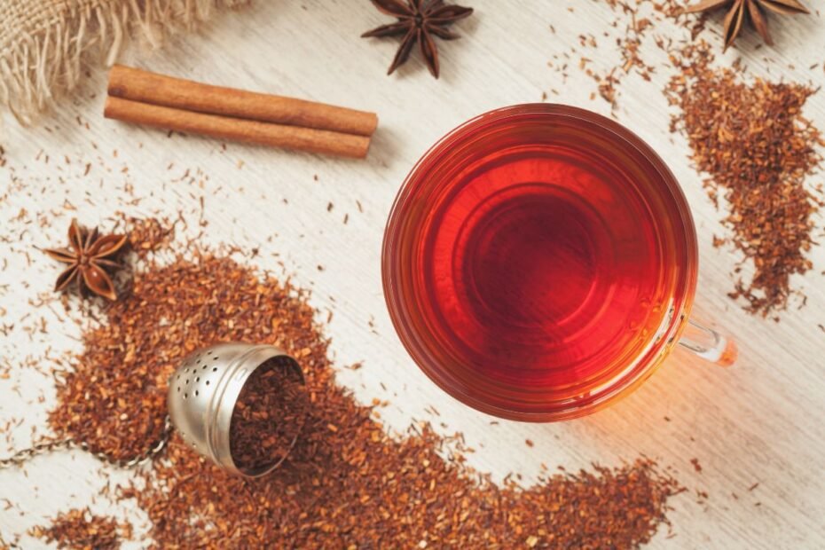 Ceașcă de ceai rooibos alături de rooibos măcinat și un baton de scorțișoară